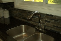 Stainless steel sink, with a dark granite countertop and dark backsplashing. Great ways to contrast off white painted cabinetry!